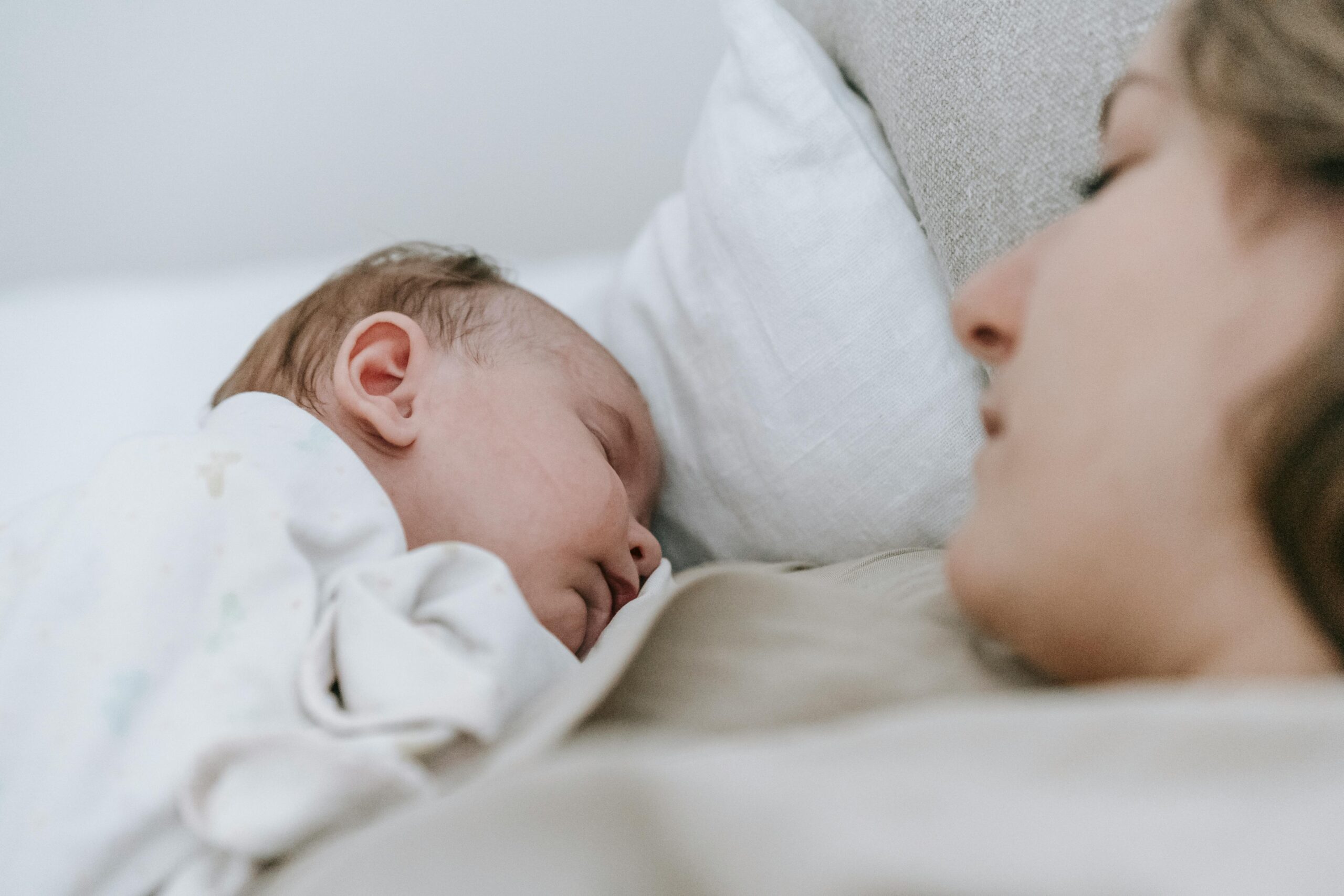 A serene moment capturing a mother and baby sleeping together, depicting warmth and maternal love.